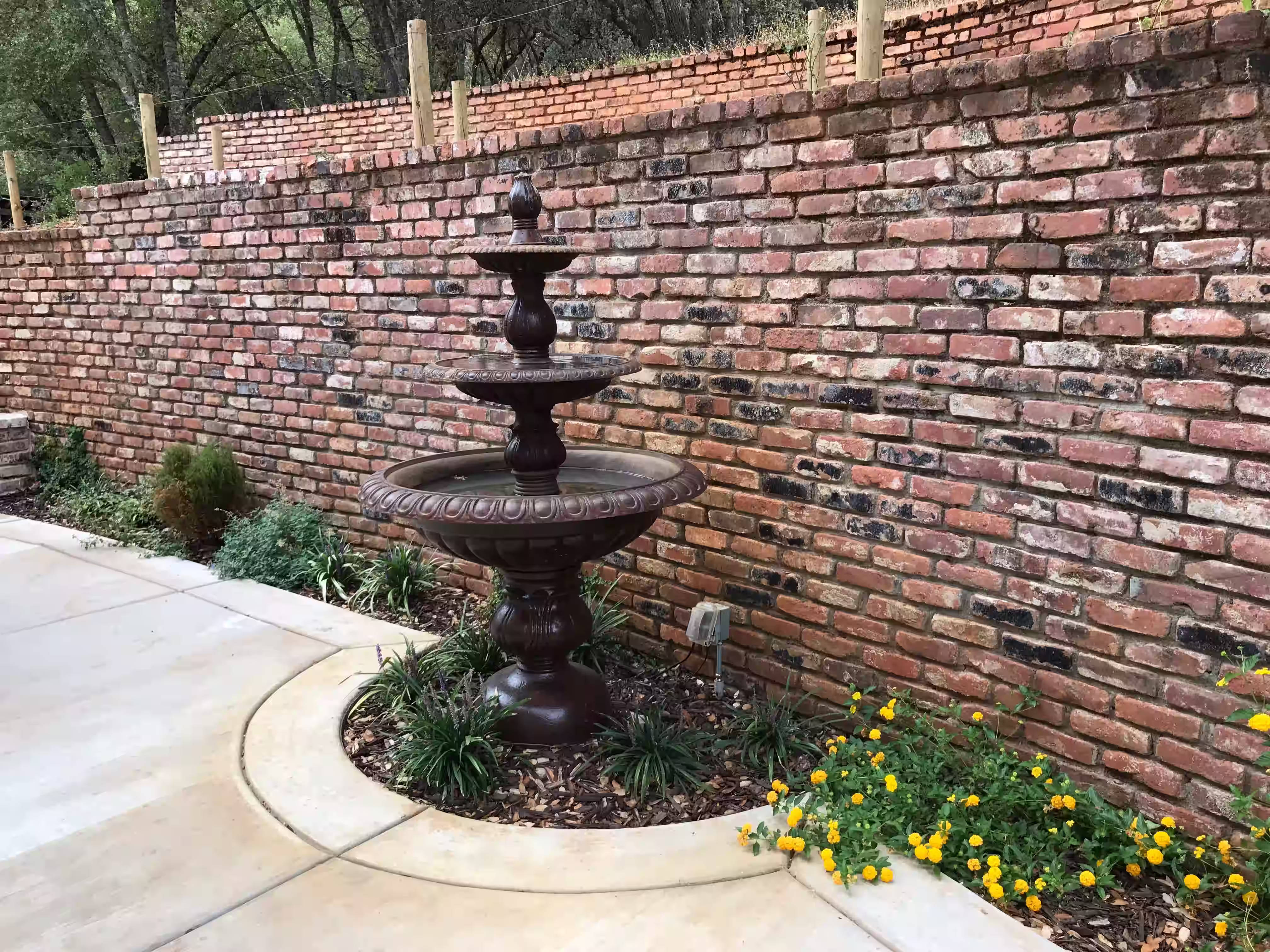 Brick and concrete hardscape installation with planter and water fountain integration